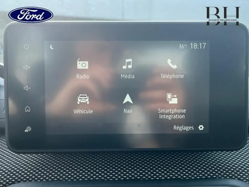 Écran tactile central du tableau de bord d’une Dacia Sandero blanc, affichant les options multimédia et navigation.