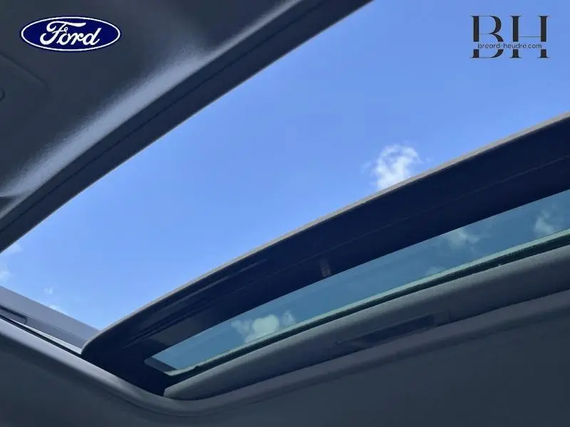 Toit ouvrant électrique ouvert vu de l'intérieur sur un ciel bleu, Dacia Sandero blanc 2023 Stepway.