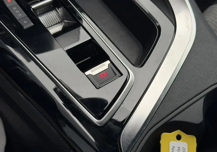 Gros plan sur la console centrale noire brillante du Peugeot 3008 2024 avec frein de stationnement électrique et sélecteur de vitesses.