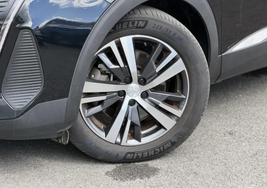 Gros plan sur la roue avant droite du Peugeot 3008 noir Perla avec jante alliage 18 pouces bi-ton diamantée.