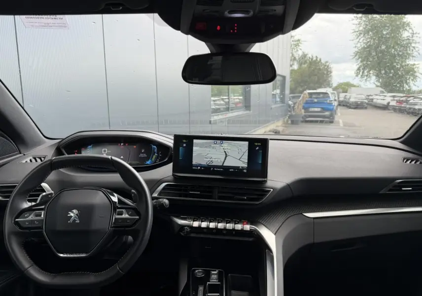Vue intérieure avant du Peugeot 3008 Plug-in Hybrid 2024, tableau de bord noir avec écran tactile central et volant compact.