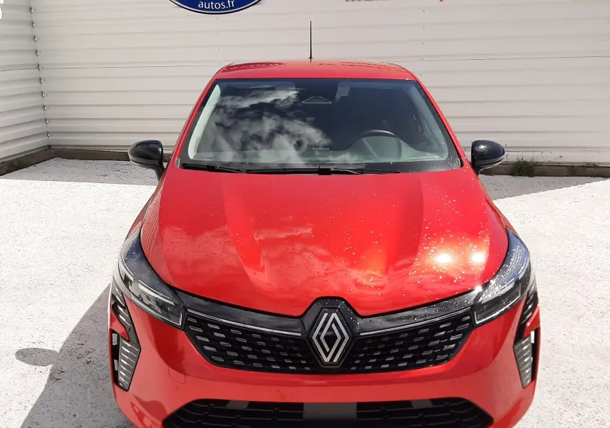 Renault Clio V rouge flamme vue de face, mettant en valeur la calandre noire et les phares LED fins.