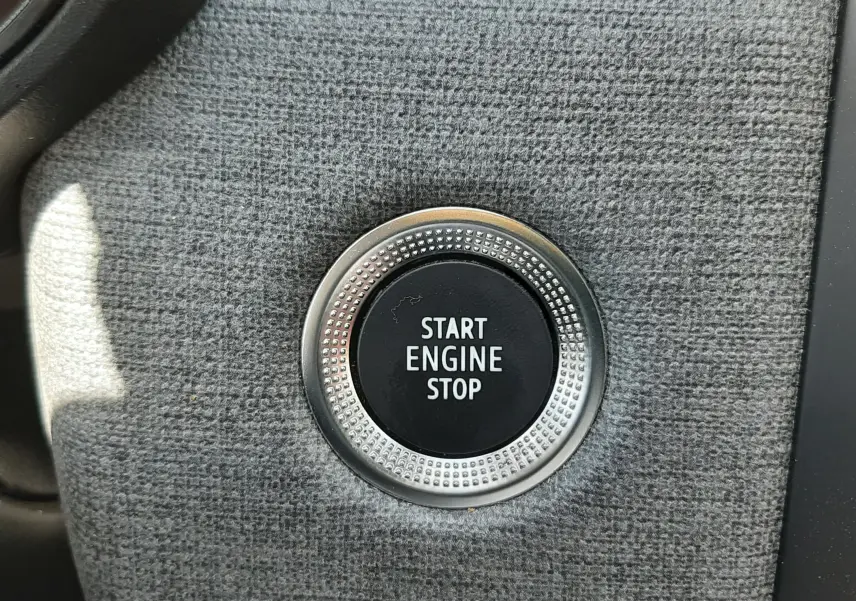 Bouton Start Engine Stop en gros plan sur la console intérieure grise de la Renault Clio V rouge flamme 2024.