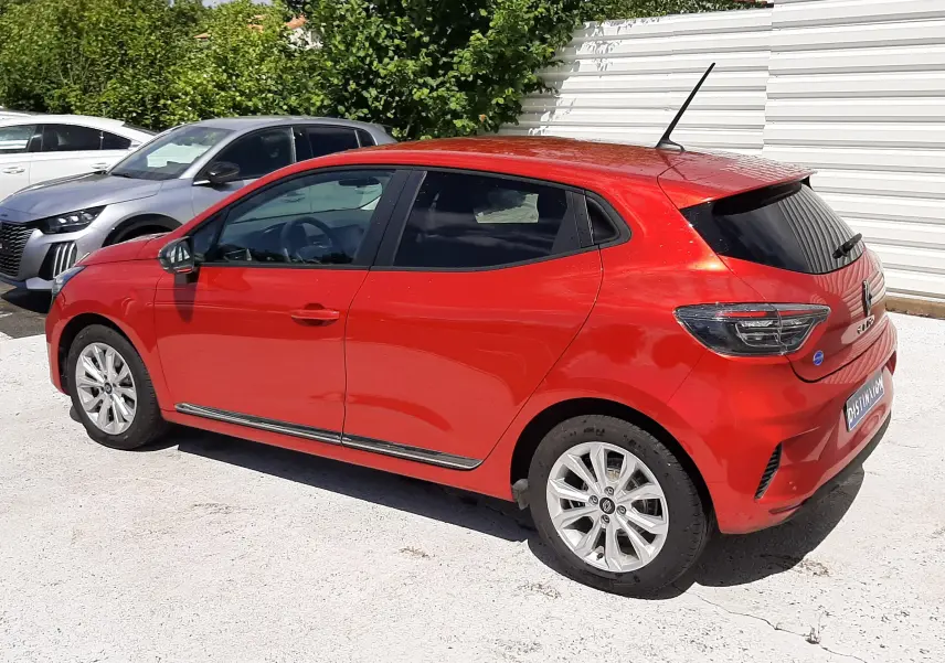 Renault Clio V rouge flamme vue de trois quarts arrière côté gauche, avec vitres teintées et jantes alliage.