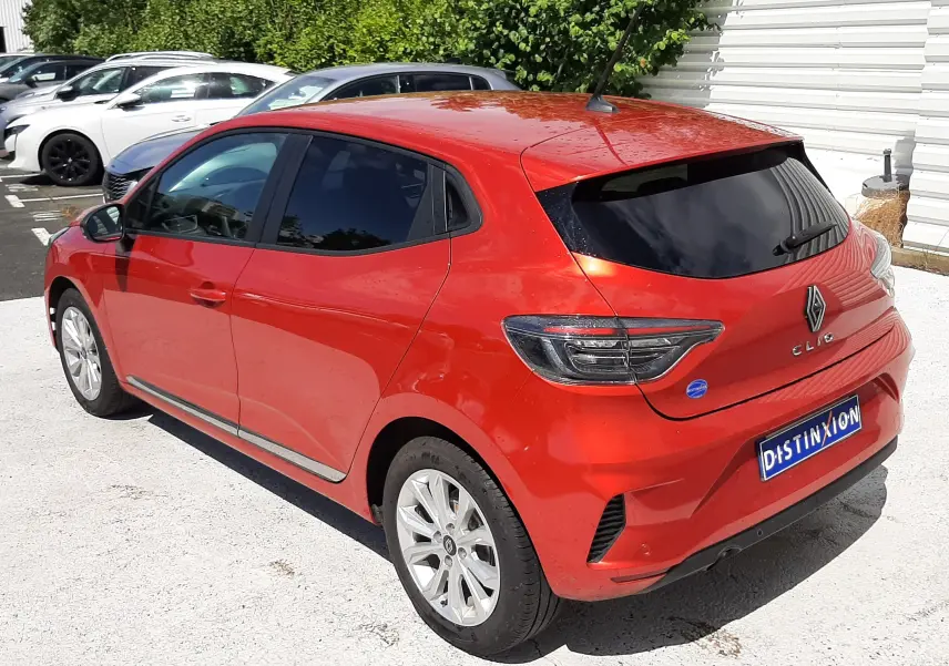 Renault Clio V rouge flamme vue 3/4 arrière droit, avec vitres teintées et feux arrière modernes.