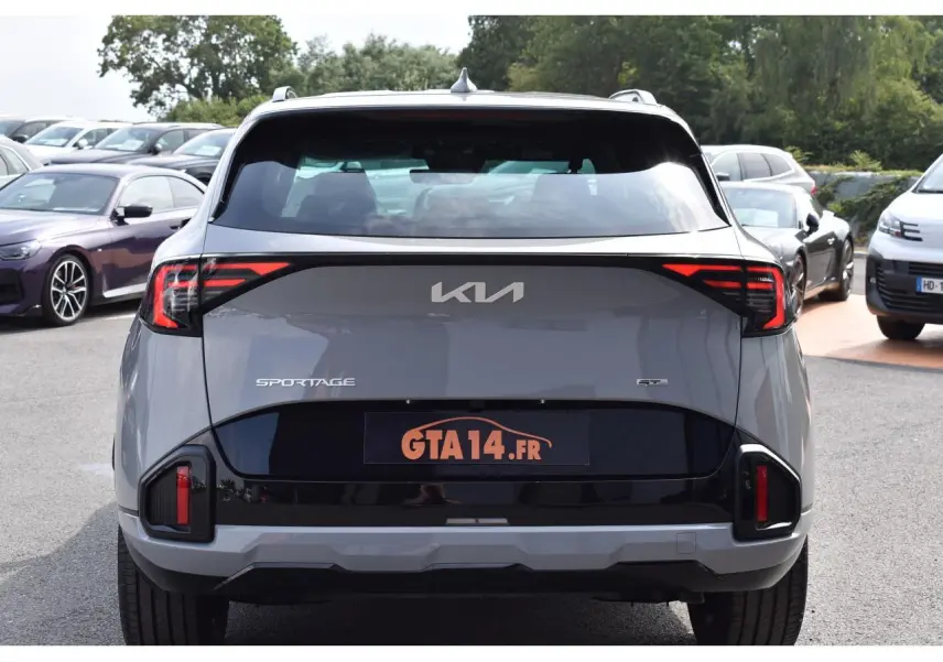 Vue arrière d'un Kia Sportage hybride gris loup avec feux LED et logo central sur fond noir brillant.