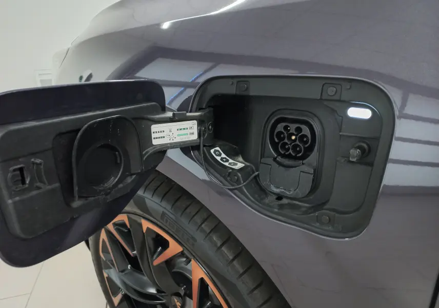 Gros plan sur la trappe de recharge côté gauche du CUPRA Terramar violet intersidéral avec jante 20'' cuivrée visible.