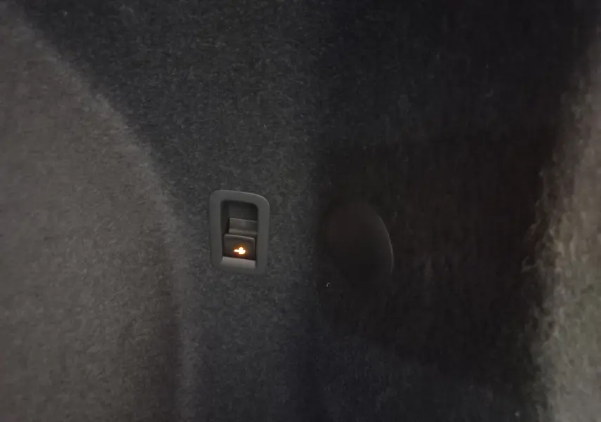 Intérieur du coffre de la CUPRA TERRAMAR 2025, détail du bouton d'ouverture électrique du hayon sur revêtement noir.