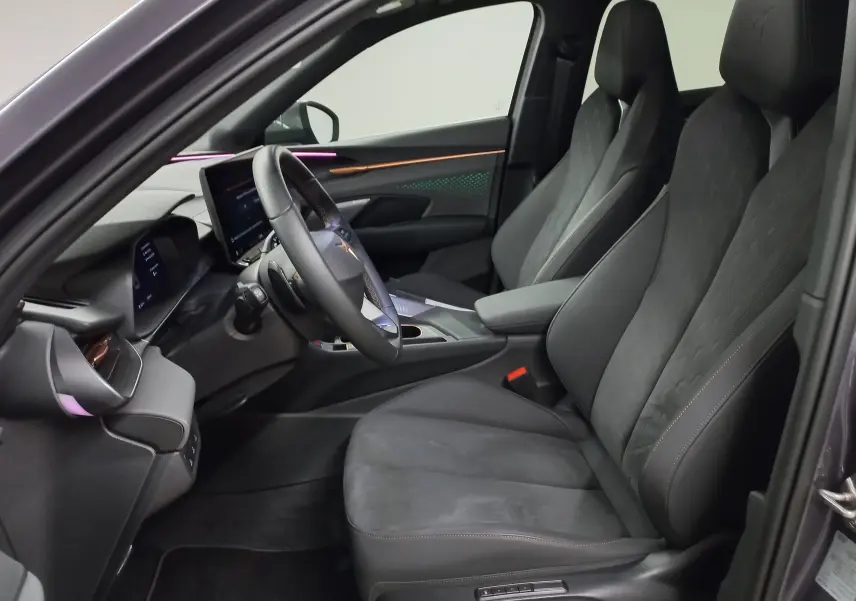 Intérieur côté conducteur de la CUPRA TERRAMAR 2025, sièges noirs, éclairage d’ambiance violet et inserts cuivrés visibles.