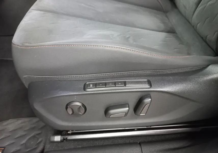 Gros plan sur la commande de réglage électrique du siège conducteur en tissu gris avec surpiqûres cuivrées du CUPRA Terramar.