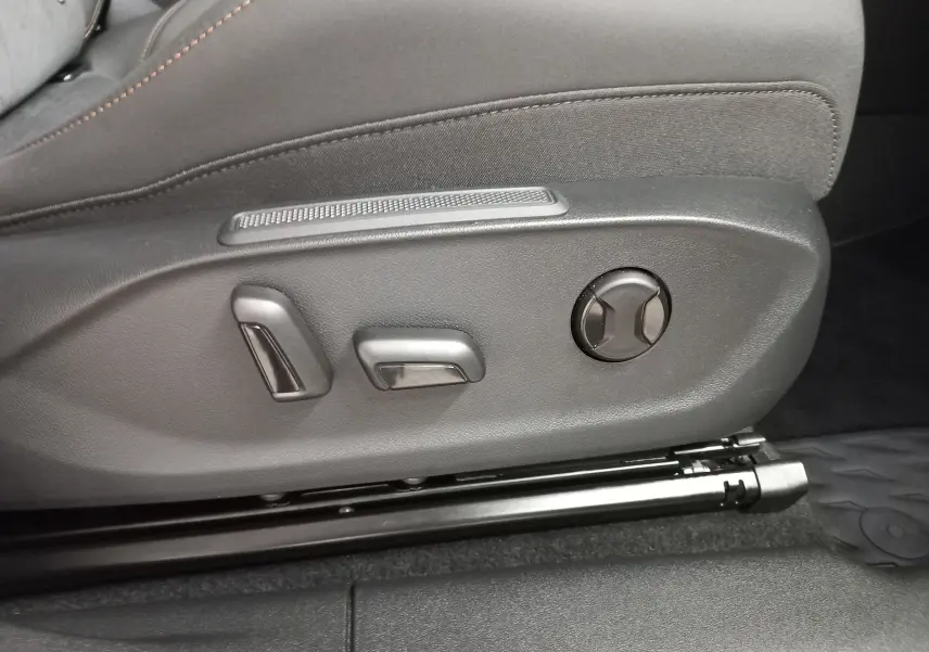 Gros plan sur les commandes de réglage électrique du siège avant en tissu gris foncé, intérieur du CUPRA TERRAMAR.