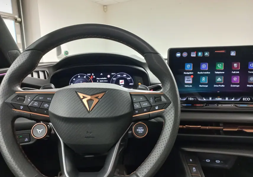 Vue intérieure centrée sur le volant noir avec logo cuivré et écran tactile du tableau de bord du CUPRA TERRAMAR 2025.