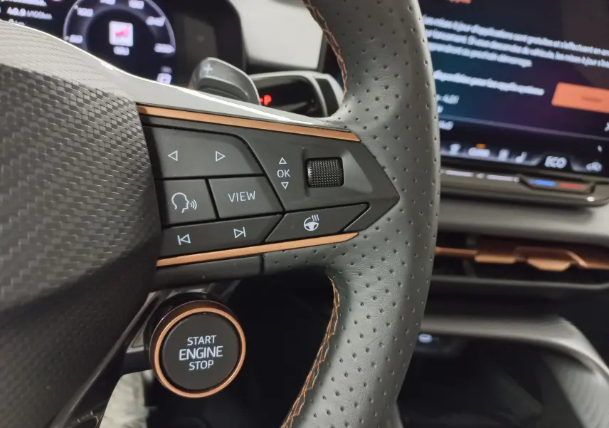 Gros plan sur le volant perforé noir avec surpiqûres cuivrées et bouton start/stop du CUPRA Terramar 2025.