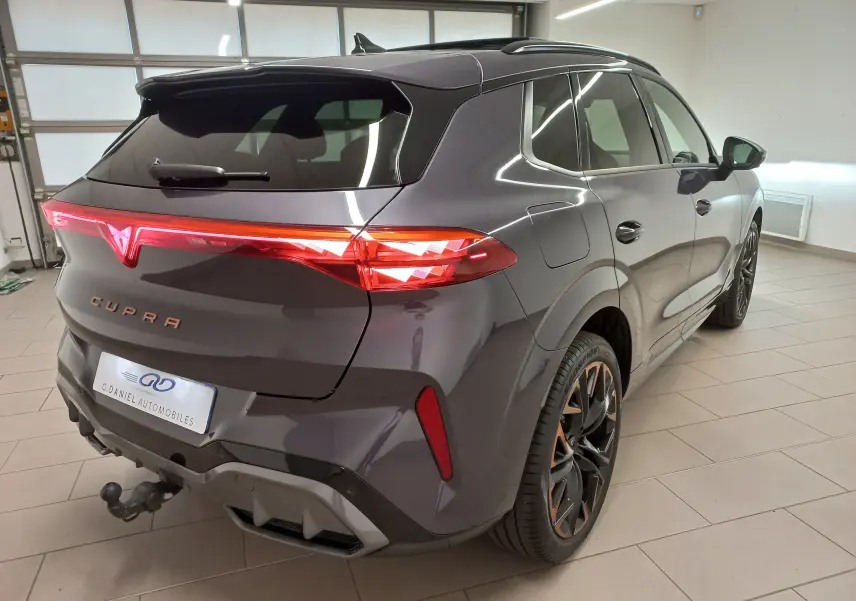 Vue 3/4 arrière droit du CUPRA TERRAMAR violet intersidéral avec jantes cuivrées et attelage escamotable en intérieur showroom.