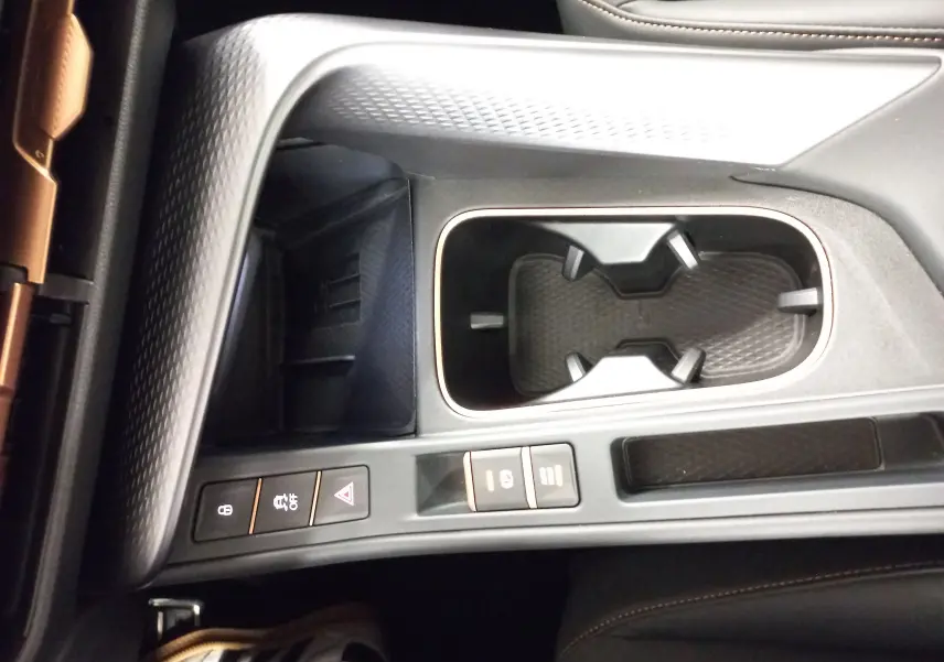 Gros plan sur la console centrale du CUPRA TERRAMAR 2025, avec porte-gobelets, boutons de contrôle et finitions noires texturées.