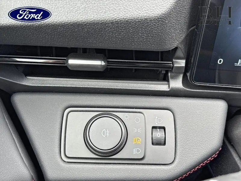 Gros plan sur la commande des phares dans l'habitacle du Ford Puma 2025, finition ST-Line X, avec surpiqûres rouges.