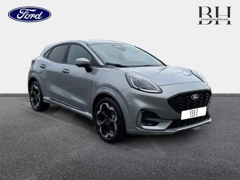 Ford Puma 2025 gris Solar métallisé en vue 3/4 avant droit avec jantes alliage noires et calandre noire.