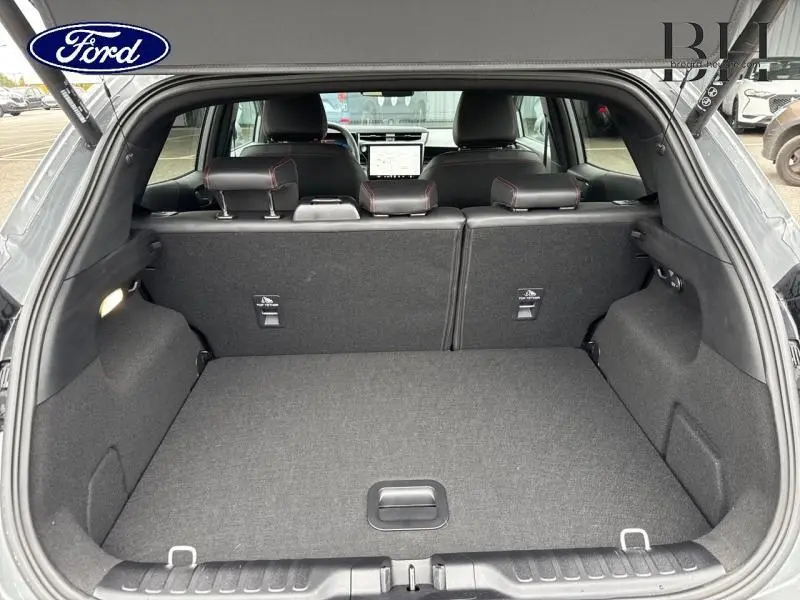 Coffre ouvert du Ford Puma gris Solar Métallisée, vue arrière montrant banquette et intérieur noir avec surpiqûres rouges.