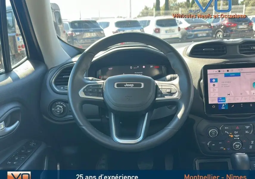 Vue intérieure centrée sur le volant Jeep noir du Renegade 2024 avec écran tactile et commandes au volant visibles.