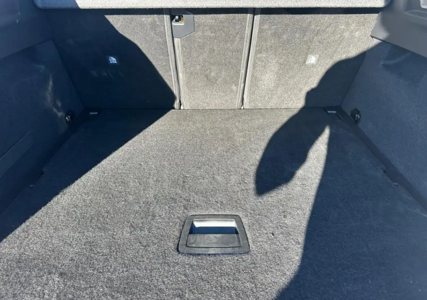 Coffre spacieux et vide du Peugeot 3008 Hybrid blanc, vue plongeante sur le tapis de sol gris.