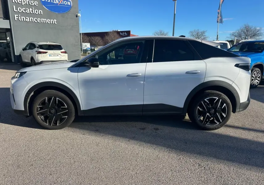 Vue de profil côté gauche d’un Peugeot 3008 Hybrid blanc avec jantes alliage noires de 19 pouces sur parking extérieur.