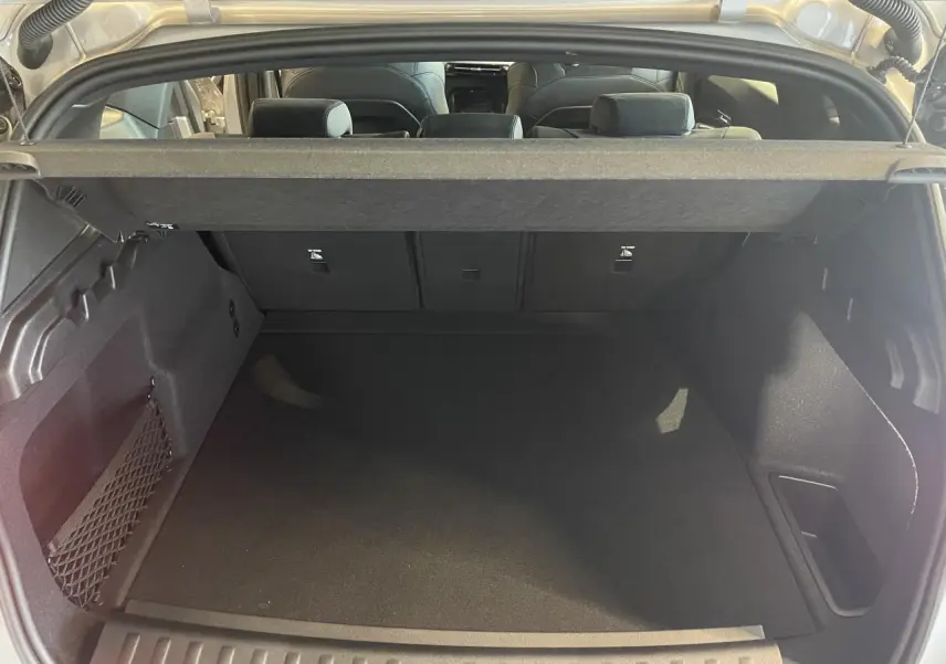 Coffre spacieux ouvert d’un BMW X1 xDrive 20d 2024 en couleur Spacesilber Metallic, avec filet de rangement latéral.