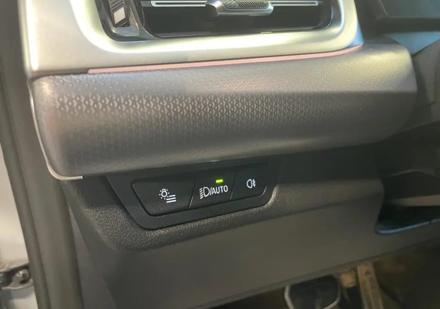 Détail des commandes d’éclairage avec bouton auto allumé sur la partie inférieure gauche du tableau de bord d’un BMW X1 Spacesilber Metallic.