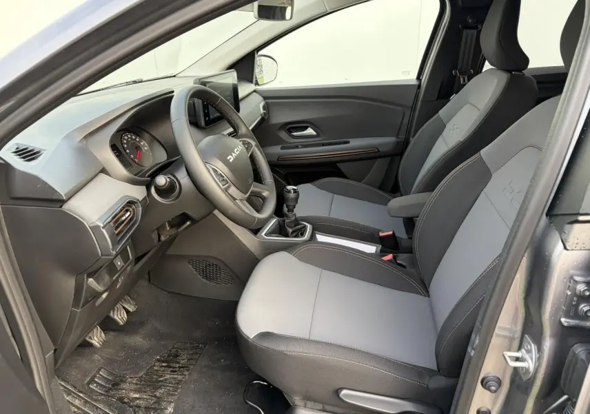 Vue intérieure côté conducteur du Dacia Jogger gris schiste, montrant les sièges bicolores et le volant avec logo Dacia.