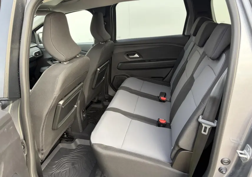 Vue intérieure côté droit sur la banquette arrière grise et noire du Dacia Jogger 2025 avec tablettes aviation au dos des sièges avant.