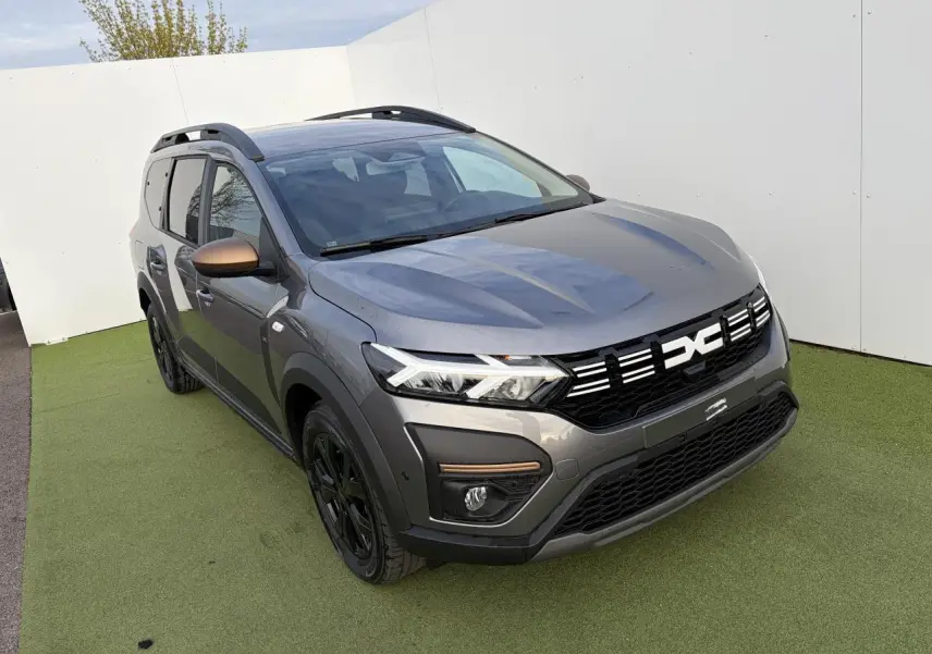 Vue 3/4 avant droite du Dacia Jogger gris schiste métal avec calandre noire et rétroviseurs brun cuivré.