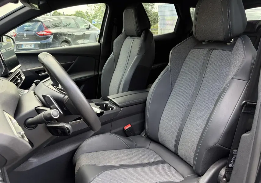 Vue intérieure côté conducteur du Peugeot 3008 2024, sièges bi-matière gris et noir avec accoudoir central.