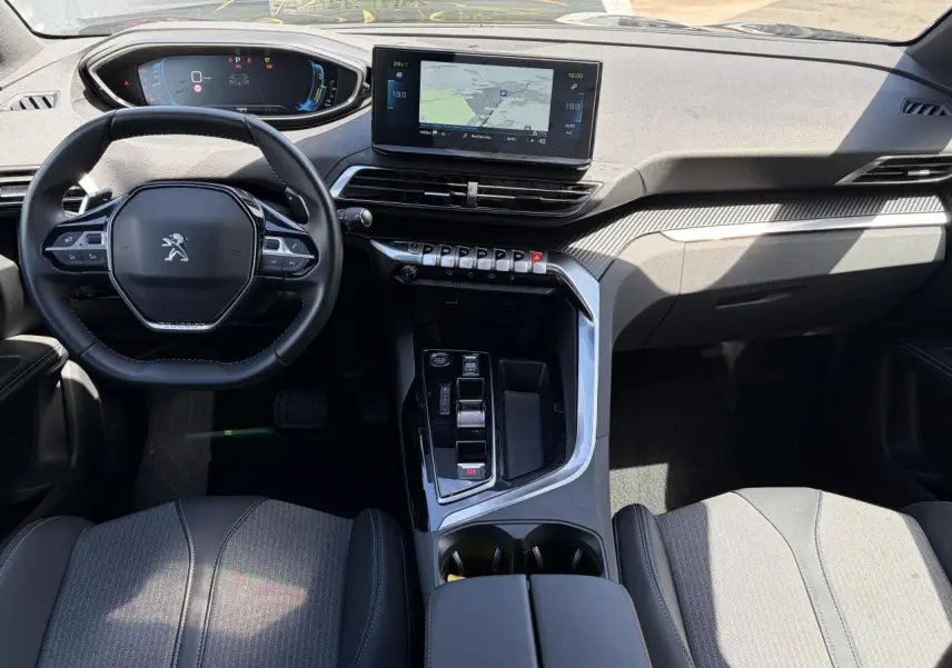 Vue intérieure avant du Peugeot 3008 Plug-in Hybrid 2024, volant compact, écran tactile central et console moderne noire.