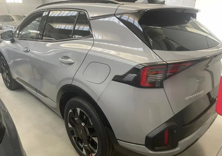 Vue 3/4 arrière droite du KIA SPORTAGE hybride gris lunaire 2026 avec jantes noires et feux arrière LED distinctifs.