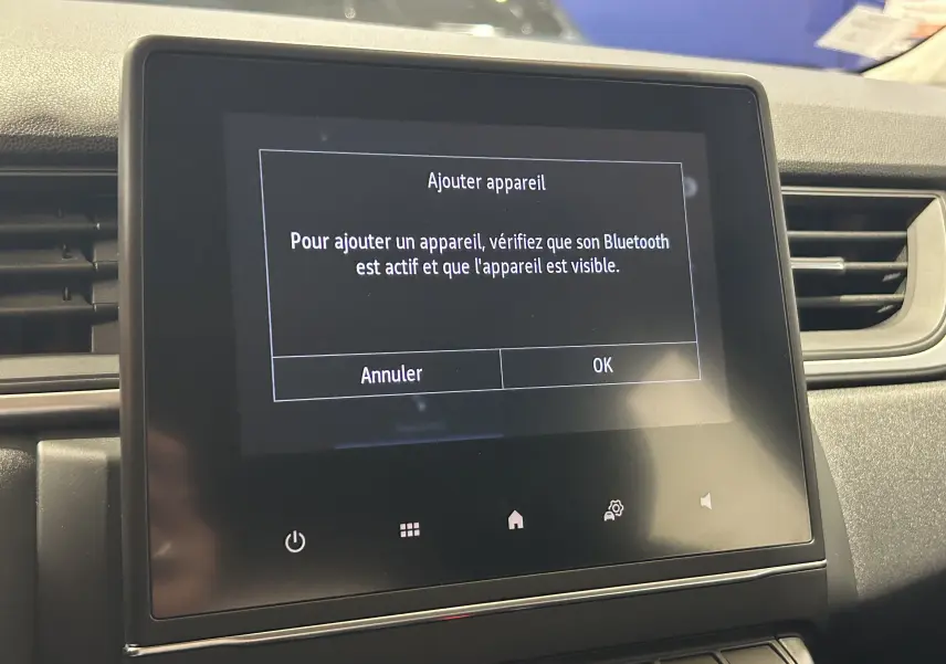 Écran tactile central du tableau de bord du Renault Captur gris 2022 affichant un message Bluetooth.