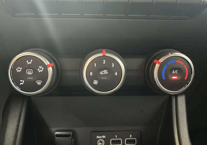 Gros plan sur les commandes de climatisation manuelle du Renault Captur gris, avec réglages de température, ventilation et air conditionné.