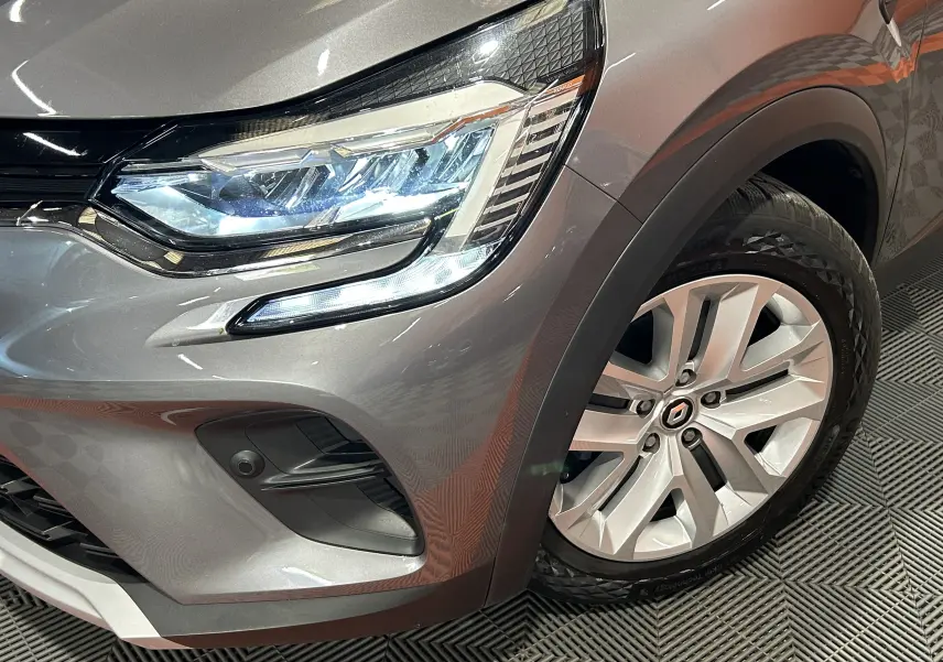 Gros plan sur l'avant droit gris du Renault Captur II avec phare LED allumé et jante alliage distinctive.