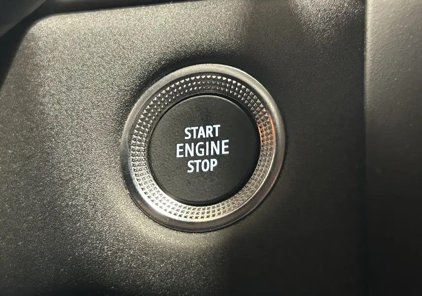Gros plan sur le bouton Start Engine Stop entouré d’un cercle texturé dans l’habitacle noir du Renault Captur gris.