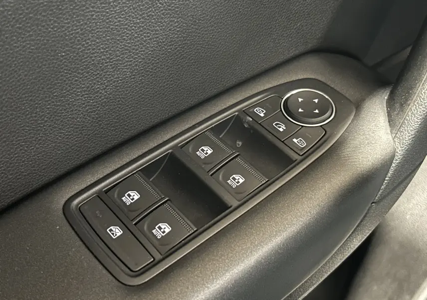 Gros plan sur les commandes électriques des vitres et rétroviseurs côté conducteur d’un Renault Captur gris 2022.