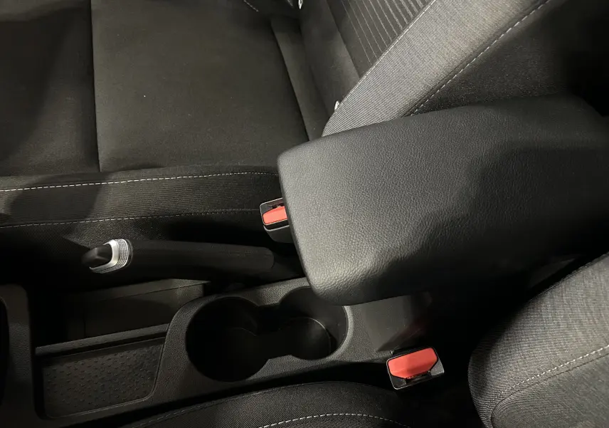 Détail de l'accoudoir central noir et frein à main manuel sur les sièges tissu gris du Renault Captur 2022.