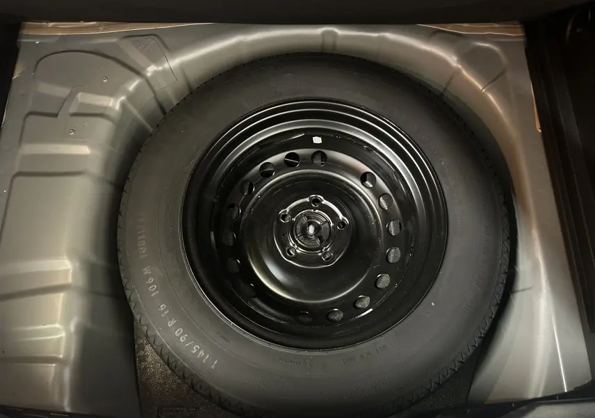 Vue en plongée sur la roue de secours noire logée dans le coffre gris d’un Renault Captur 2022.