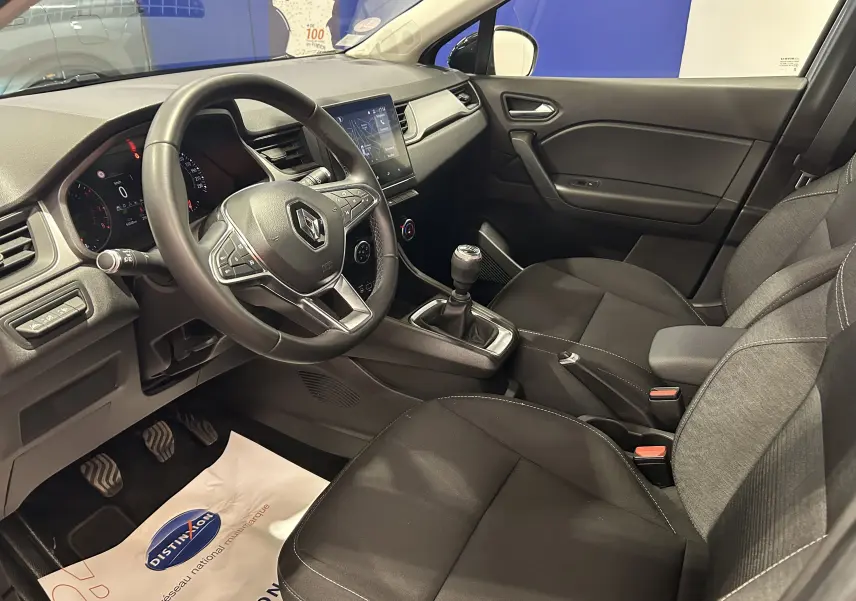 Vue intérieure côté conducteur du Renault Captur gris 2022, avec volant multifonction et boîte manuelle visible.