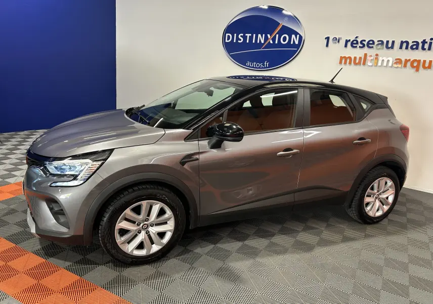 Renault Captur gris en vue de profil côté gauche, avec jantes alliage et rétroviseurs noirs, en intérieur showroom.