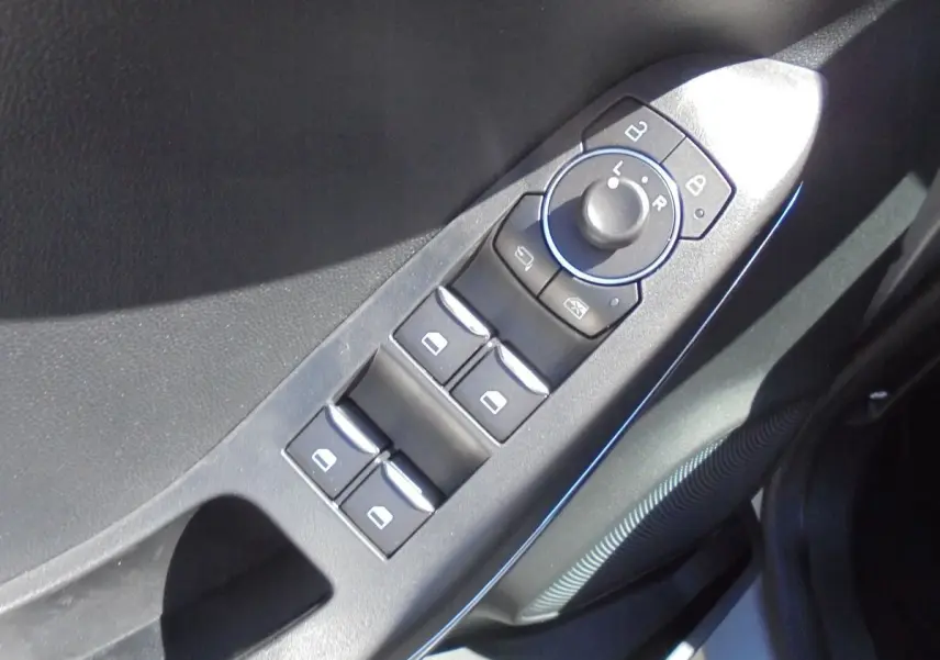Gros plan sur les commandes des vitres et rétroviseurs côté conducteur d'une Ford Puma gris Solar Metal.
