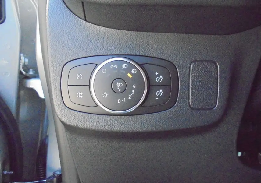 Gros plan sur le bouton de réglage des phares du Ford Puma gris Solar Metal, côté gauche du tableau de bord.