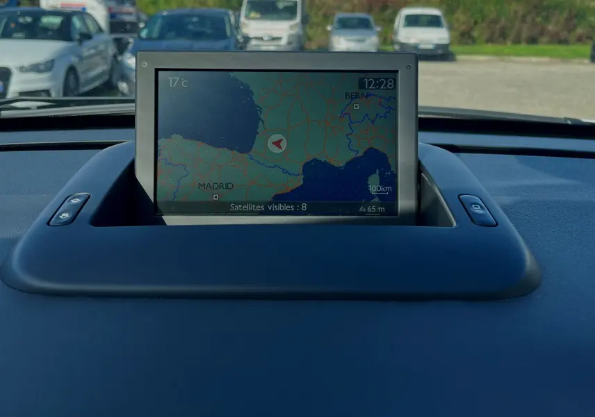 Écran GPS déployé sur le tableau de bord noir d'un Peugeot 3008 gris clair, vue intérieure frontale.