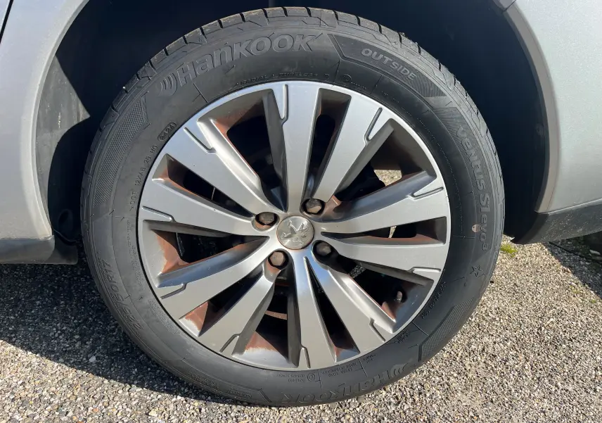 Gros plan sur la roue avant droite d’un Peugeot 3008 gris clair de 2014 avec jante alliage et pneu Hankook.