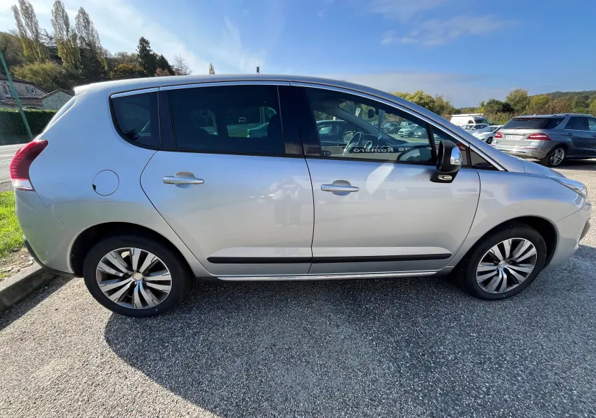 Profil côté gauche d'un Peugeot 3008 gris clair de 2014, version 1.6 HDI 115 Allure, avec jantes alliage et vitres teintées.
