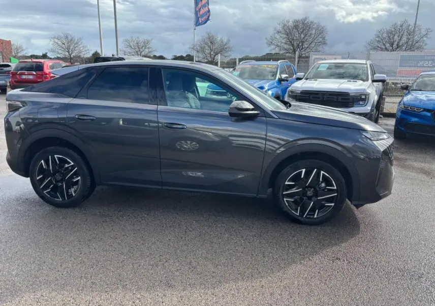 Vue de profil côté gauche d’un Peugeot 3008 Hybrid gris avec jantes alliage 19 pouces, sur parking extérieur.
