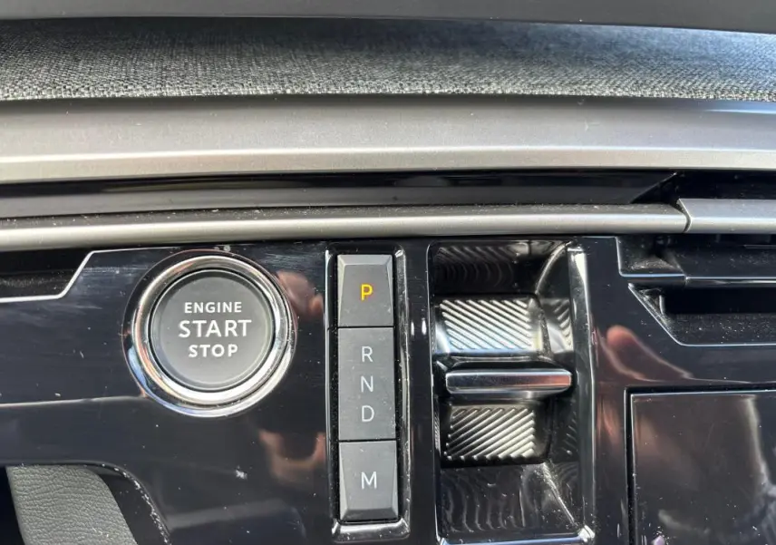 Gros plan sur la console centrale noire du Peugeot 3008 Hybrid 145 e-DCS6 Allure avec bouton start/stop et commandes de boîte auto.