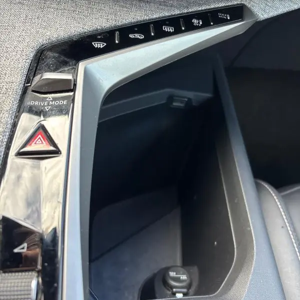 Vue rapprochée de la console centrale du Peugeot 3008 Hybrid 145 e-DCS6 Allure 2025, avec commandes et rangement noir.
